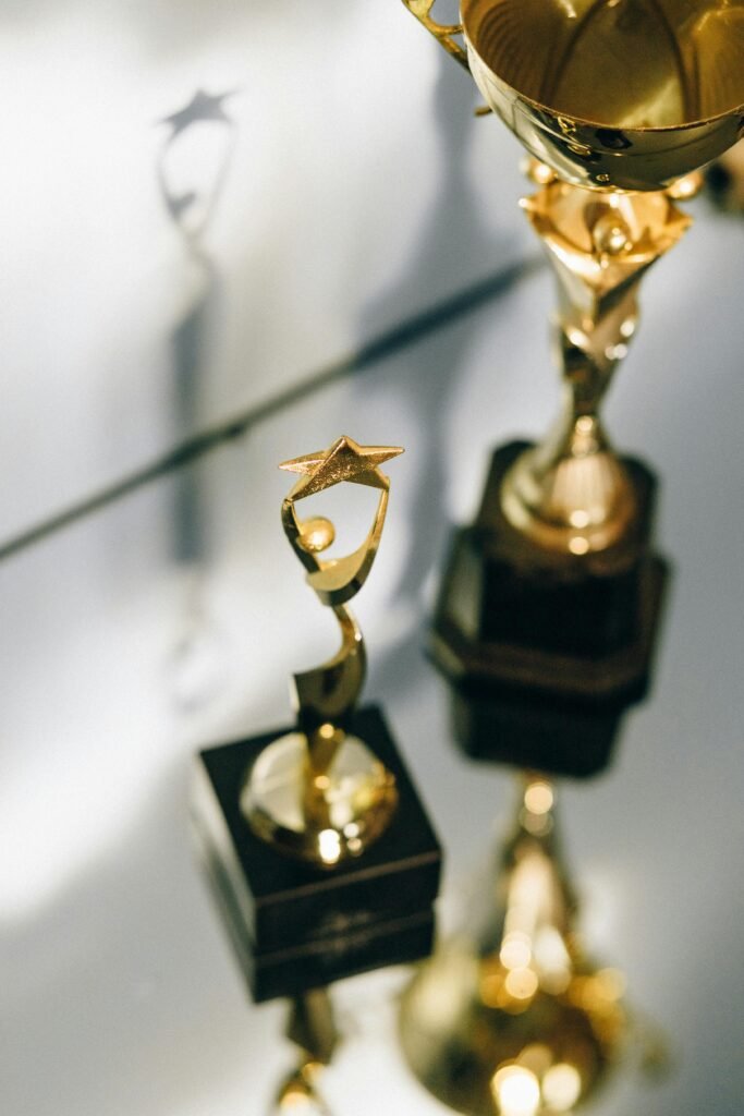 Close-up of shiny golden star trophies reflecting on a glass surface, perfect for award-themed concepts.