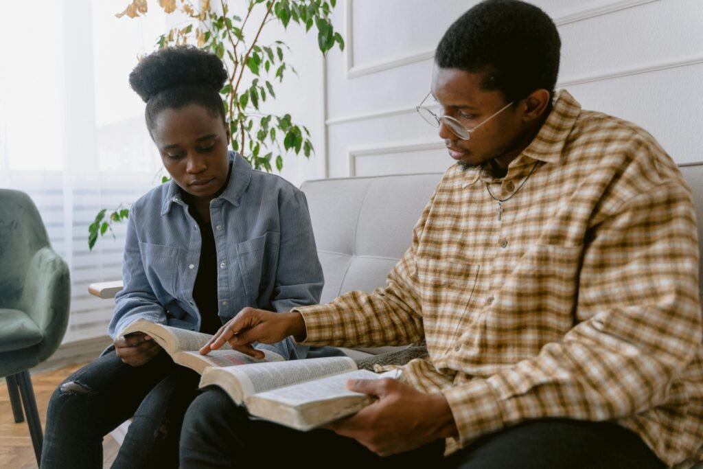 Two individuals engaged in reading the Bible together, depicting faith and togetherness.